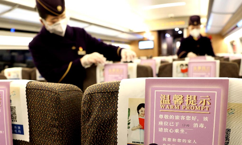 Crew members place disinfection notices on train G1724 in east China's Shanghai, Jan. 16, 2022.Photo:Xinhua