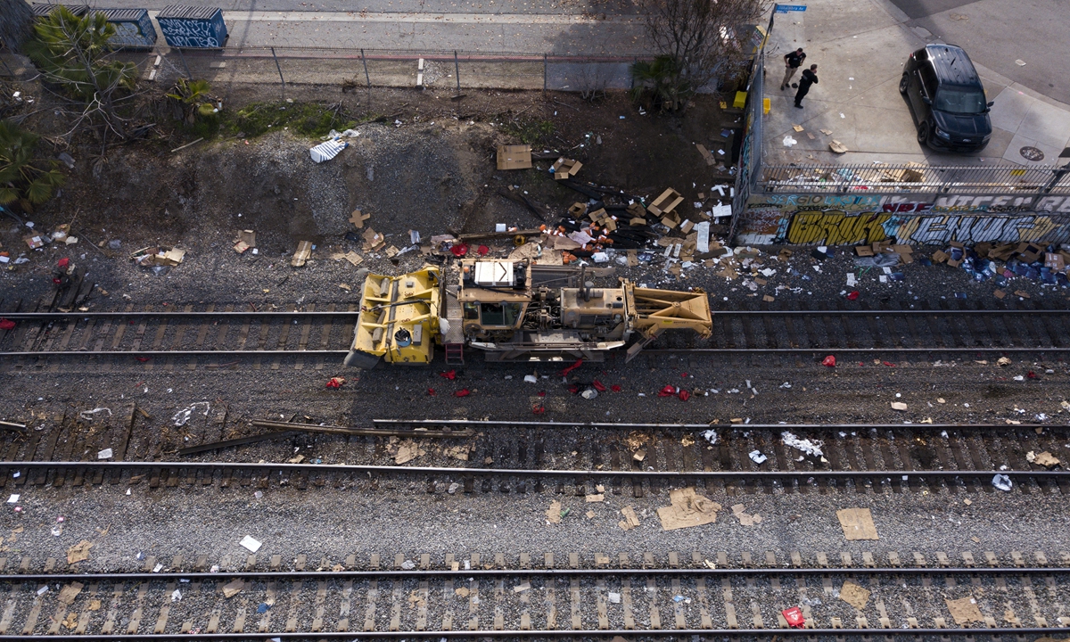 An aerial image from January 16, 2022 shows law enforcement officers as they keep watch (R) over railroad workers repairing a section of Union Pacific train tracks after a train derailed from the tracks, which are littered with thousands of opened boxes and packages stolen from cargo shipping containers targeted by thieves as the trains stop in downtown Los Angeles, California on January 16, 2022. AFP