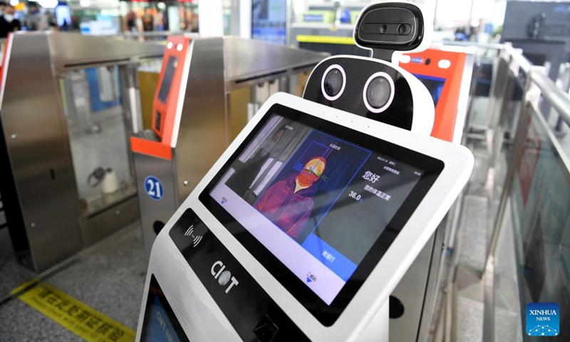 Da Bai, an intelligent temperature measuring robot, measures a passenger's body temperature at the entrance of Hefei South Railway Station in Hefei, east China's Anhui Province, Jan. 18, 2022. Air environment automatic sterilizer robot Xiao Chuang, intelligent temperature measuring robot Da Bai and ground cleaning and disinfecting robot Xiao De have been in service for COVID-19 prevention and control during the annual Spring Festival travel rush in Hefei.(Photo: Xinhua)