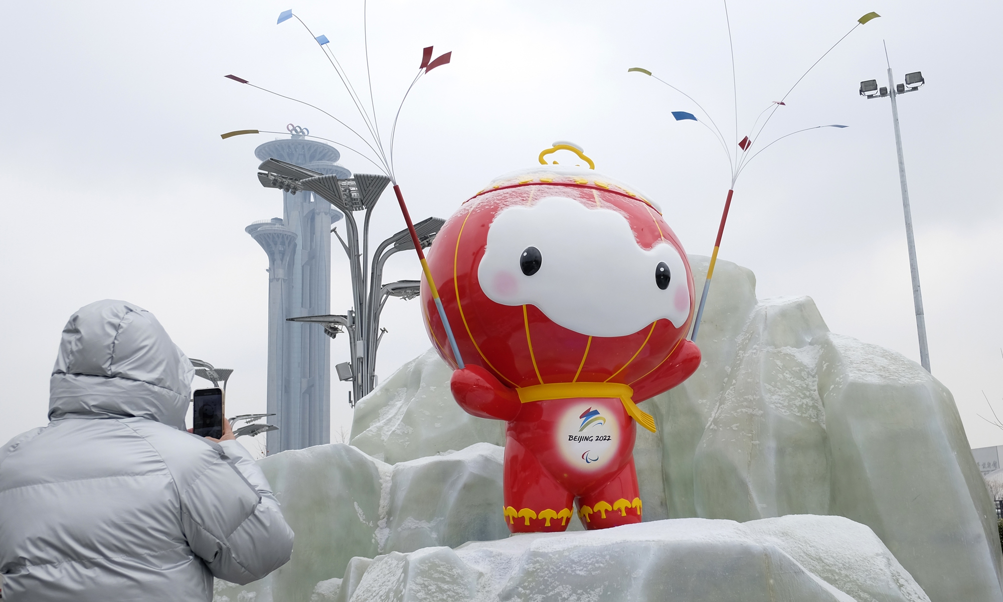 A Beijing resident takes a photo of the Beijing Winter Olympic Games mascot 