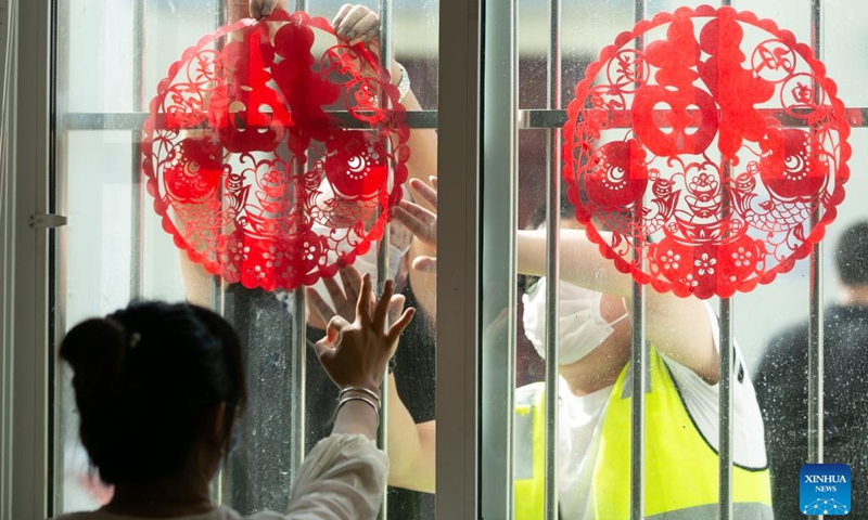 Staff members of the China-Laos Railway Luang Prabang Operation Management Center paste paper-cutting artworks on windows at the center in Luang Prabang, Laos, Jan. 22, 2022.Photo:Xinhua