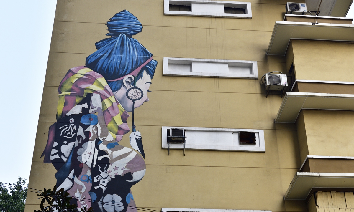 An old residential building in Southwest China's Chongqing Municipality is painted with a modern art drawing of a blue-haired girl. The neighborhood, now 