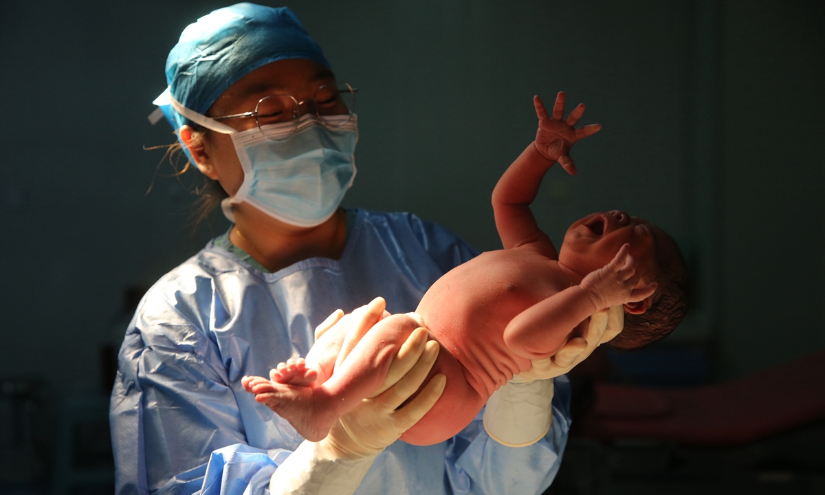 A nurse holds a new born baby in a hospital in Zhengzhou, Henan Province on January 1, 2022. Photo: VCG