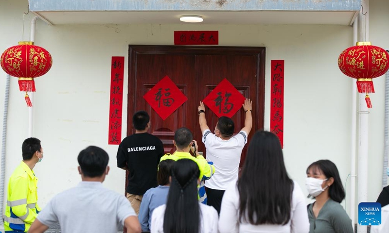 Staff members of the China-Laos Railway Luang Prabang Operation Management Center paste Chinese calligraphy Fu, which means good fortune, on doors in Luang Prabang, Laos, Jan. 22, 2022.Photo:Xinhua