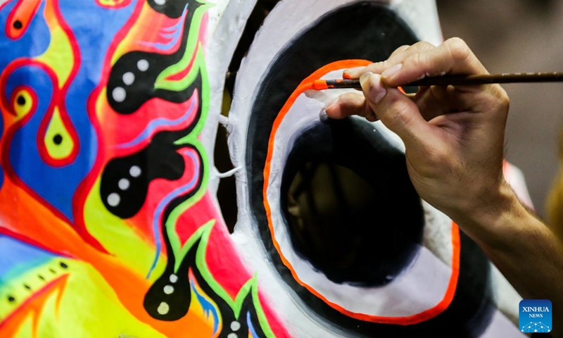 A member of a costume workshop paints a lion head costume in Manila, the Philippines, Jan. 24, 2022. Although most of performances for the upcoming Chinese lunar New Year celebrations are canceled in Manila due to epidemic prevention and control measures, local dragon and lion costume workshops still work on creations for customers who are ready to buy or rent the costumes to display.(Photo: Xinhua)