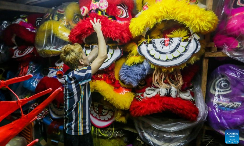 A member of a costume workshop arranges costumes in Manila, the Philippines, Jan. 24, 2022. Although most of performances for the upcoming Chinese lunar New Year celebrations are canceled in Manila due to epidemic prevention and control measures, local dragon and lion costume workshops still work on creations for customers who are ready to buy or rent the costumes to display. (Photo: Xinhua)