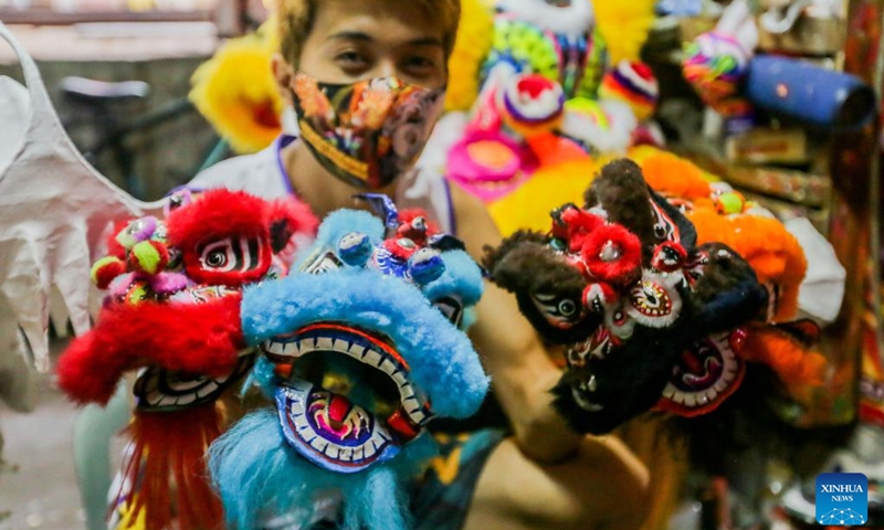 A member of a costume workshop shows miniature lion head costumes in Manila, the Philippines, Jan. 24, 2022. Although most of performances for the upcoming Chinese lunar New Year celebrations are canceled in Manila due to epidemic prevention and control measures, local dragon and lion costume workshops still work on creations for customers who are ready to buy or rent the costumes to display. (Photo: Xinhua)