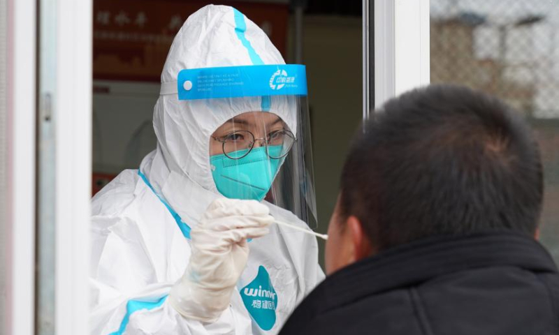A medical worker takes a swab sample from a resident at a COVID-19 testing site in Xicheng District in Beijing, capital of China, Jan. 26, 2022. (Xinhua）