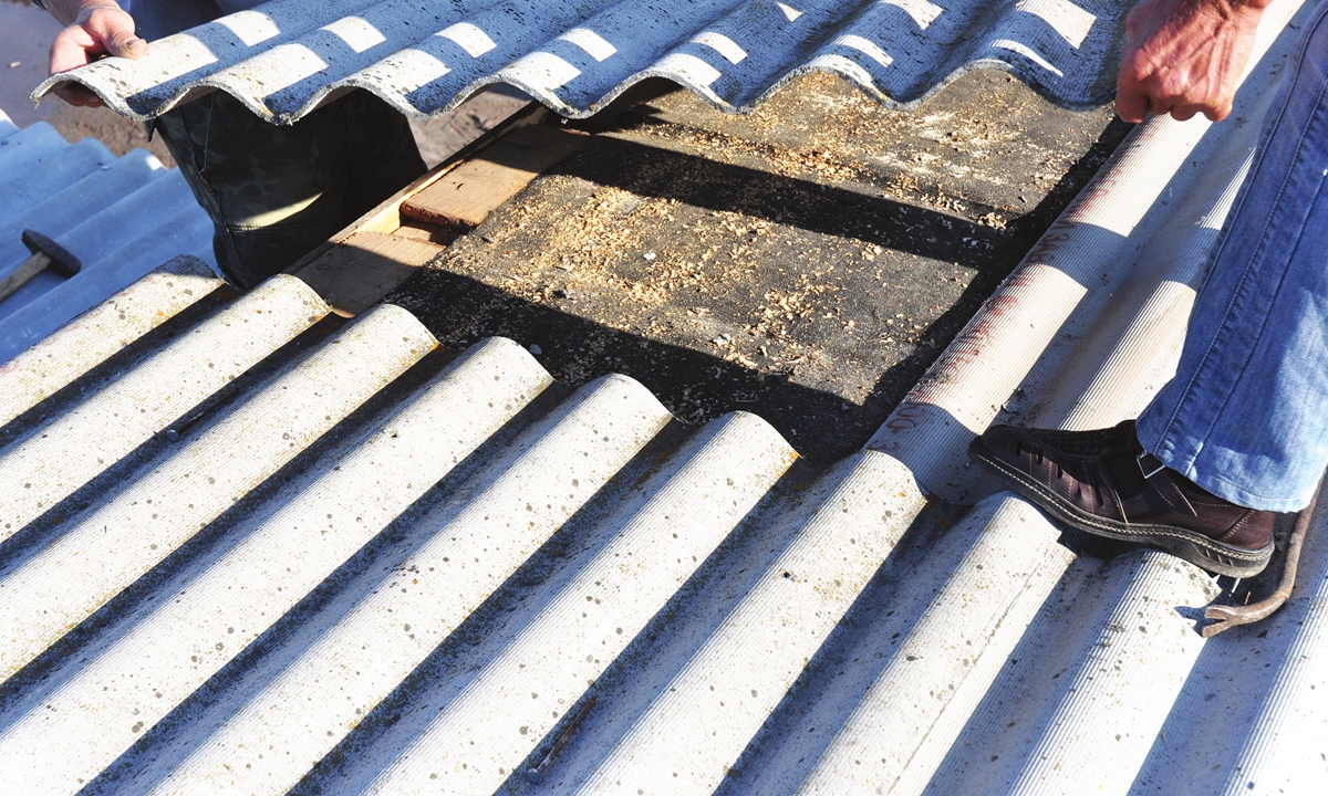 Workers repair asbestos roofs. Photo: VCG