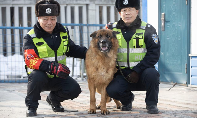 Patrollmen Wang Hongbin (R), Yu Zhenlong and patrol dog Hu Zi pose for a group photo at a patrol stand near Daqing West Railway Station in Daqing, northeast China's Heilongjiang Province, Jan. 24, 2022. Hu Zi, a 14-year-old patrol dog working for the Harbin-Qiqihar railway, the country's northernmost high speed railway, will retire after its last mission during this year's Spring Festival travel rush.(Photo: Xinhua)