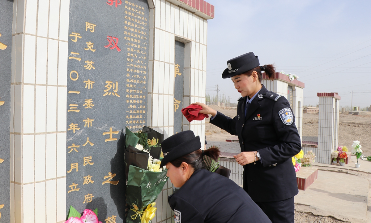 Uniformed officers lay flowers at the grave of Gao Shuang, one of the many heroes who met their end at the front line while conducting a counter-terrorism mission. Photo: Courtesy of Liao Linbo