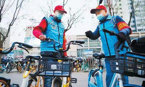 Photo shows Tao Zhenguo,a volunteer of Beijing's dual Olympics, with his grandson.Photo: Beijing Daily