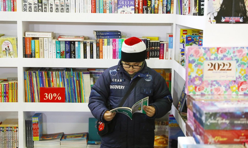 A boy reads a book while visiting the Cairo International Book Fair held in Cairo, Egypt, on Jan. 27, 2022.(Photo: Xinhua)