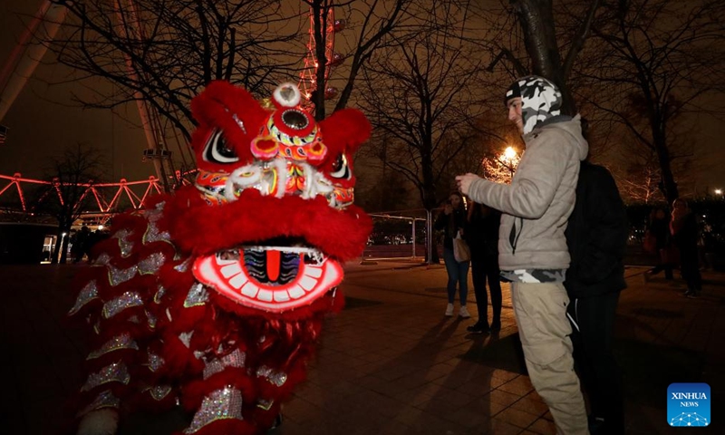Traditional Chinese lion dancers perform in front of the London Eye which is lit up in red to celebrate the upcoming Chinese New Year in London, Britain, on Jan. 28, 2022.Photo:Xinhua