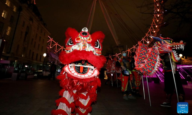 Traditional Chinese lion dancers perform in front of the London Eye which is lit up in red to celebrate the upcoming Chinese New Year in London, Britain, on Jan. 28, 2022.Photo:Xinhua