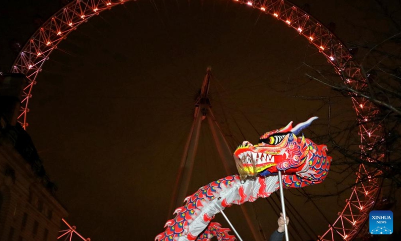Traditional Chinese lion dancers perform in front of the London Eye which is lit up in red to celebrate the upcoming Chinese New Year in London, Britain, on Jan. 28, 2022.Photo:Xinhua
