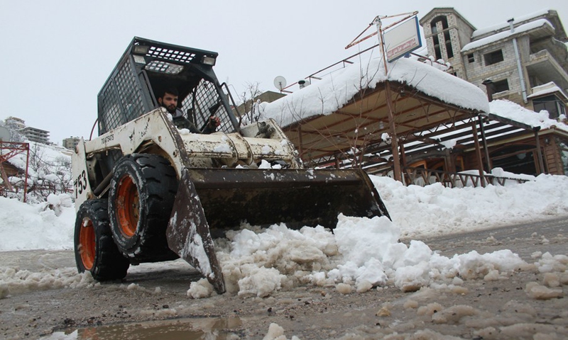 A small bulldozer opens a road in front of houses in a village in the Bcharreh district, north Lebanon, on Jan. 28, 2022.(Photo: Xinhua)
