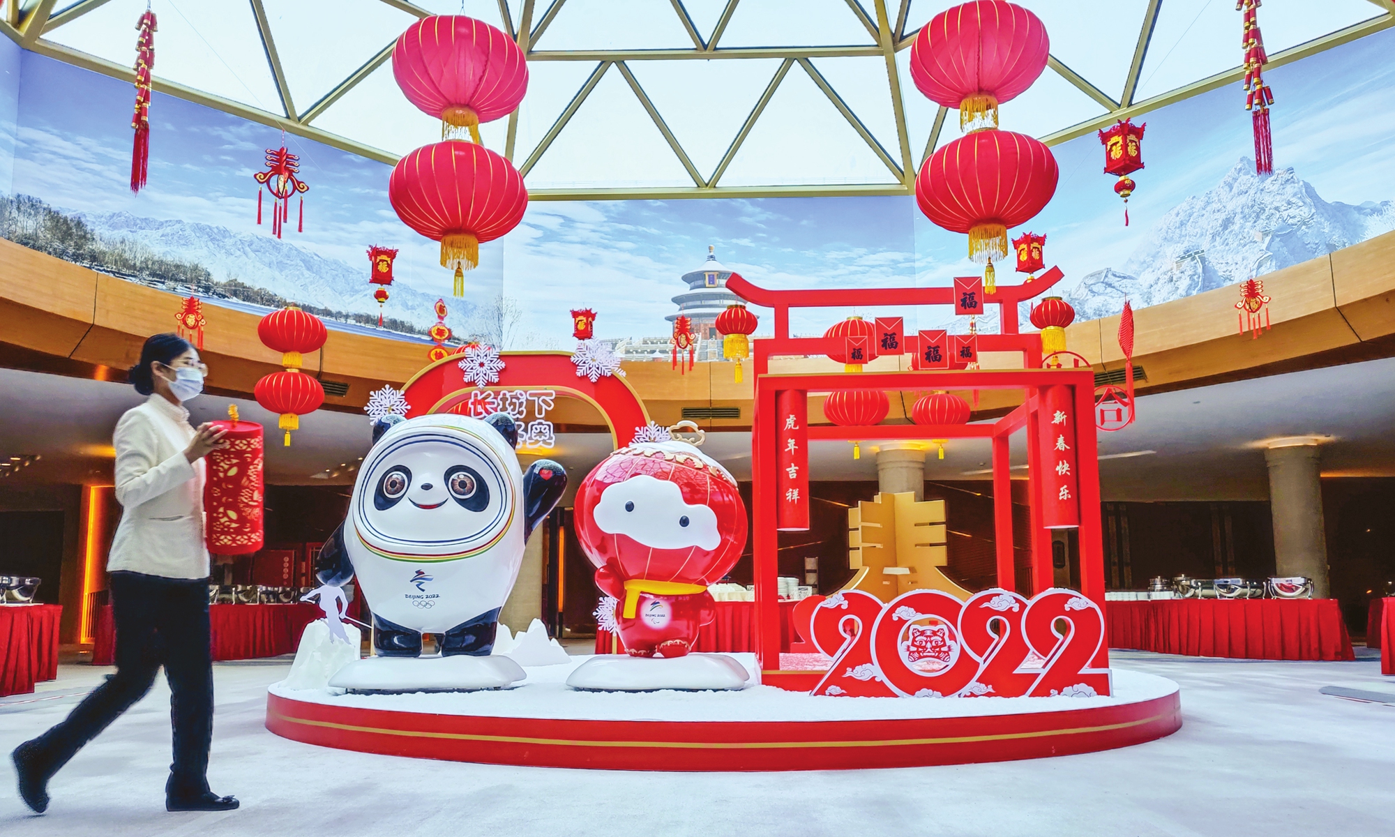 A staff member walks past mascots for Beijing 2022 Winter Olympics at the Beijing Media Center on January 29, 2022. The media center serves reporters without official Olympic accreditation. Photo: VCG