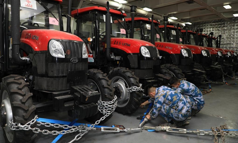 Members of People's Liberation Army (PLA) Navy fasten tractors on a ship delivering relief supplies to Tonga, Jan. 30, 2022. (Photo by Xue Chengqing/Xinhua)