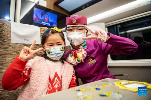 Lin Mengfan poses for a photo with a little passenger aboard a Fuxing bullet train travelling on the Chendu-Chongqing Railway in southwest China, Jan. 27, 2022.  (Xinhua/Tang Yi)


