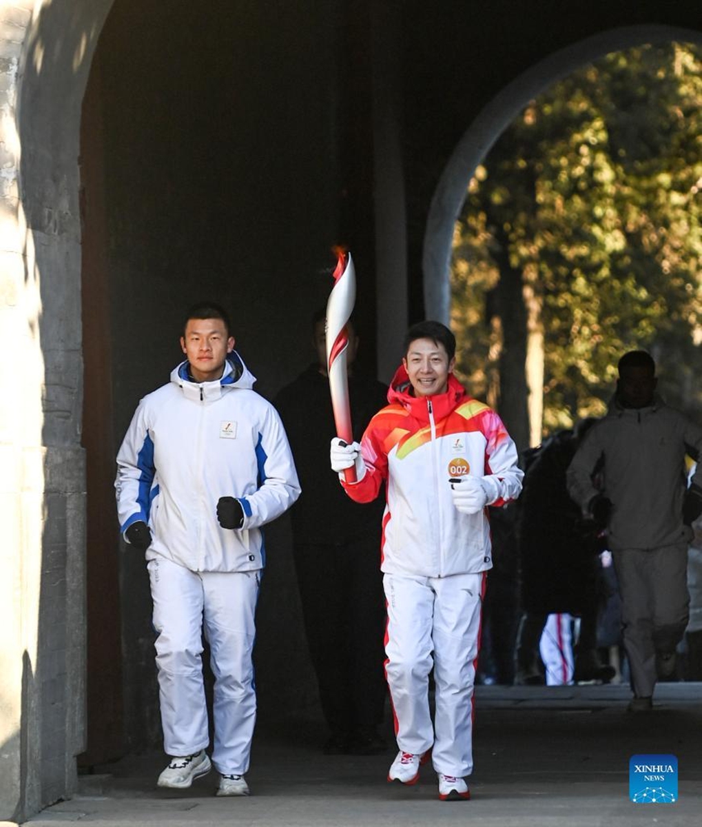 Torch bearer Sa Beining (R) runs with the torch during the Beijing 2022 Olympic Torch Relay at the Summer Palace in Beijing, capital of China, Feb. 4, 2022. (Xinhua/Chen Yehua)