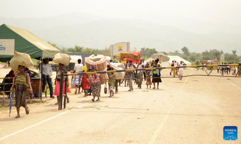 Congolese refugees carry their luggage while crossing the Busungu border post, Bundibugyo District, Western Region of Uganda, Feb. 3, 2022.Photo:Xinhua