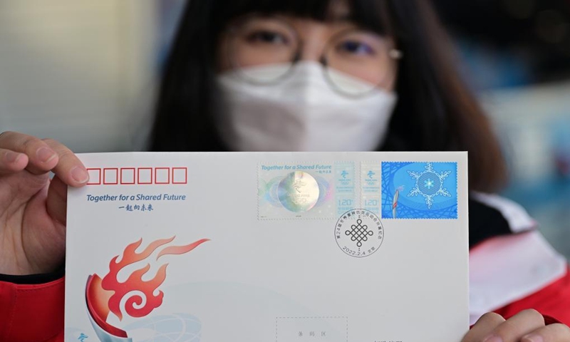 A customer shows the first day cover of commemorative stamps for the opening of the 24th Olympic Winter Games at the temporary post office of the Main Media Center for the Beijing 2022 Olympic and Paralympic Winter Games in Beijing, capital of China, Feb. 5, 2022.Photo:Xinhua