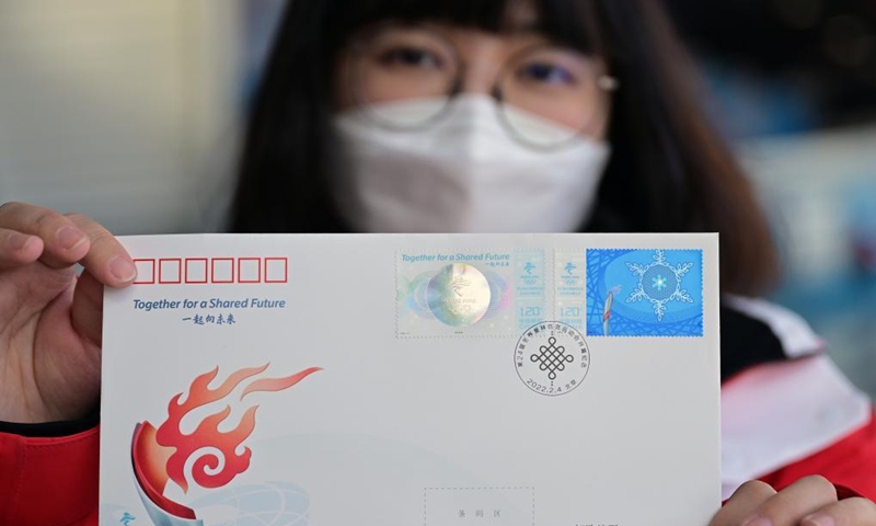 A customer shows the first day cover of commemorative stamps for the opening of the 24th Olympic Winter Games at the temporary post office of the Main Media Center for the Beijing 2022 Olympic and Paralympic Winter Games in Beijing, capital of China, Feb. 5, 2022.Photo:Xinhua