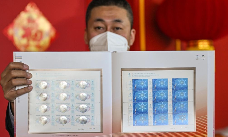 A staff member shows the commemorative stamps for the opening of the 24th Olympic Winter Games at the temporary post office of the Main Media Center for the Beijing 2022 Olympic and Paralympic Winter Games in Beijing, capital of China, Feb. 5, 2022.Photo:Xinhua