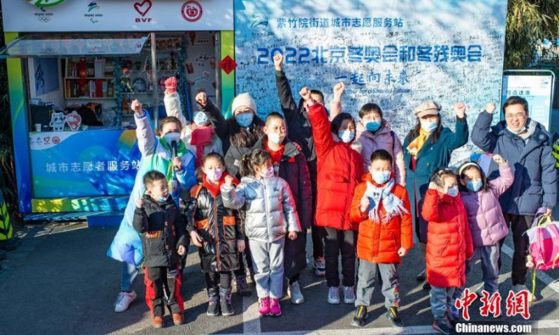 2022年2月5日，在北京紫竹园公园，一名在中央民族大学就读的台湾学生志愿者（第二排左一）与当地市民一起为北京2022年冬奥会加油。（图片来源：中新网/侯宇）