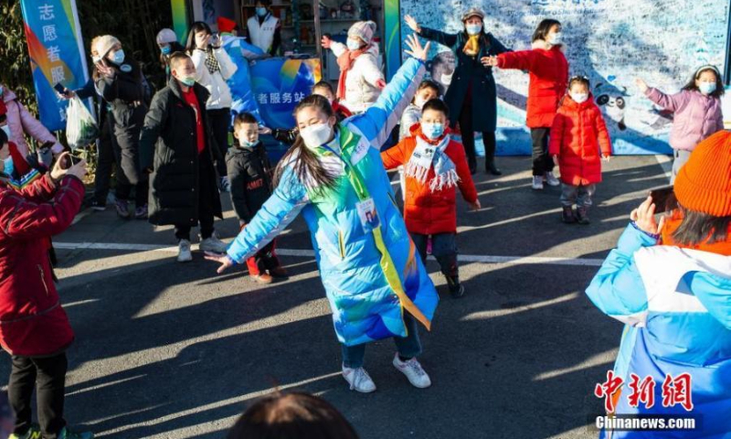 2022 年 2 月 5 日，一名在北京中央民族大学就读的台湾学生志愿者（中锋）在北京紫竹园公园与当地市民共舞，庆祝正在进行的 2022 年北京冬奥会。（图片：中新社/侯于）