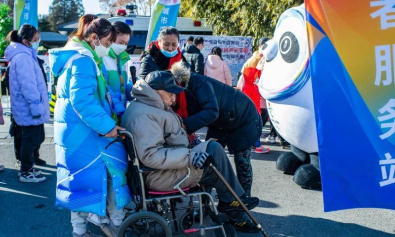 Student volunteers (first and second from left) from Taiwan and studying at Minzu University of China in Beijing help an elderly on the wheelchair at Zizhuyuan Park in Beijing, Feb. 5, 2022. (Photo: China News Service/Hou Yu)