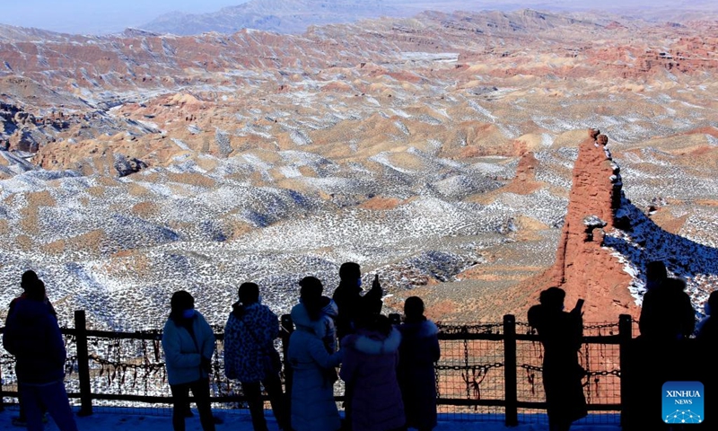 Visitors enjoy the snow scenery of Danxia landform, characterized by reddish sandstone features, at Pingshan Lake in Zhangye, northwest China's Gansu Province, Feb. 9, 2022.(Photo: Xinhua)