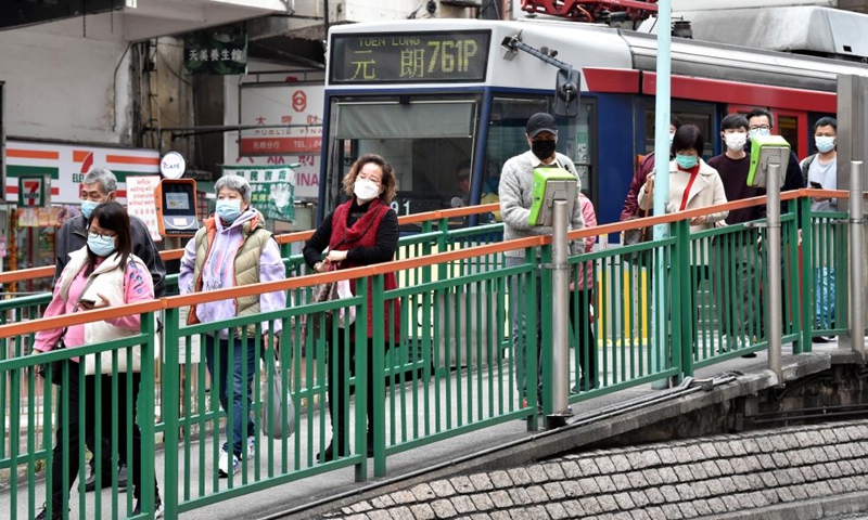 People wearing face masks walk on a street in Yuen Long, Hong Kong, south China, Feb. 9, 2022. Hong Kong registered 1,161 new cases of COVID-19 over the past 24 hours, according to data from the Center for Health Protection on Wednesday.（Xinhua）