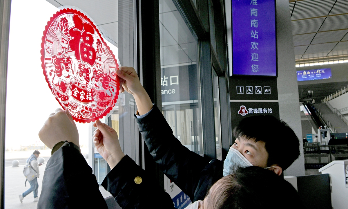 Workers stick paper-cut on the glass of a rail station's waiting hall to welcome the Spring Festival in 2022. Photo: VCG