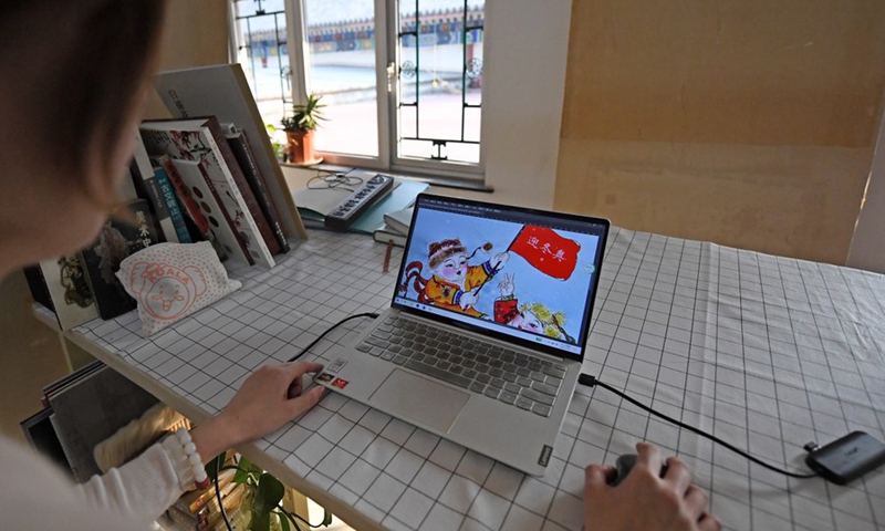 A member of the Yangliuqing woodblock painting team works on a piece of work involving elements of Olympic Winter Games on a laptop in Tianjin, north China, Feb. 10, 2022.(Photo: Xinhua)