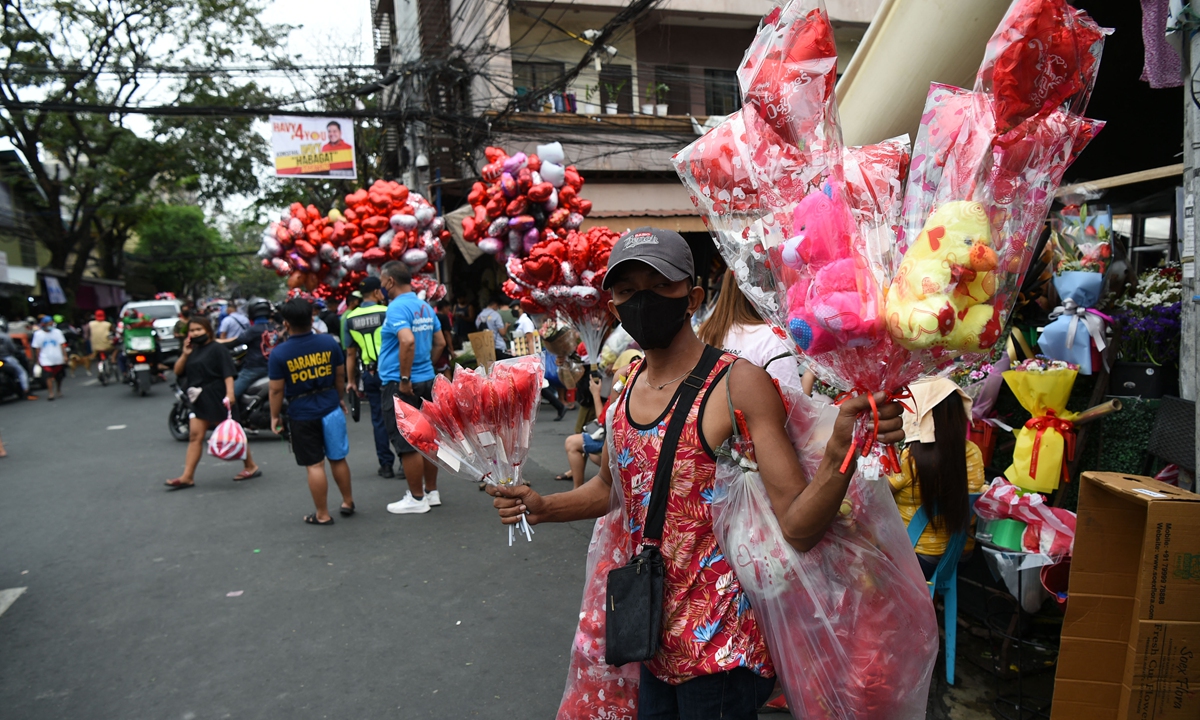 Vendors sell flowers and heart-shaped balloons at a flower street during Valentine's Day in Manila, the Philippines on February 14, 2022. With Filipinos known for their value for strong family ties, Valentine's Day is also a special day to share an unforgettable bond with the family, may it be in a fancy restaurant or over a homecooked meal, says the Manila Bulletin. Photo: AFP