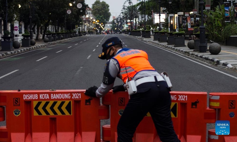 An officer from transportation department sets up road blocks during a large-scale social restriction for crowd in Bandung, West Java, Indonesia, Feb. 13, 2022.Photo:Xinhua
