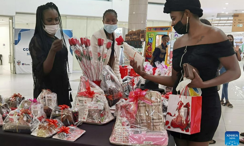 A customer shops for Valentine's Day-themed items at a mall in Windhoek, capital of Namibia, on Feb. 14, 2022. The central business district of Windhoek was a bustle of activity with red and white themed products visible at temporary stalls. The Valentine's Day observance in Namibia sparked the entrepreneurial acumen of the country's youth, powering up business growth for many.(Photo: Xinhua)