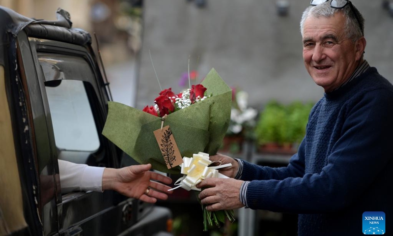 A flower shop owner hands a bouquet of flowers to a customer on Valentine's Day in Gozo, Malta, on Feb. 14, 2022.(Photo: Xinhua)