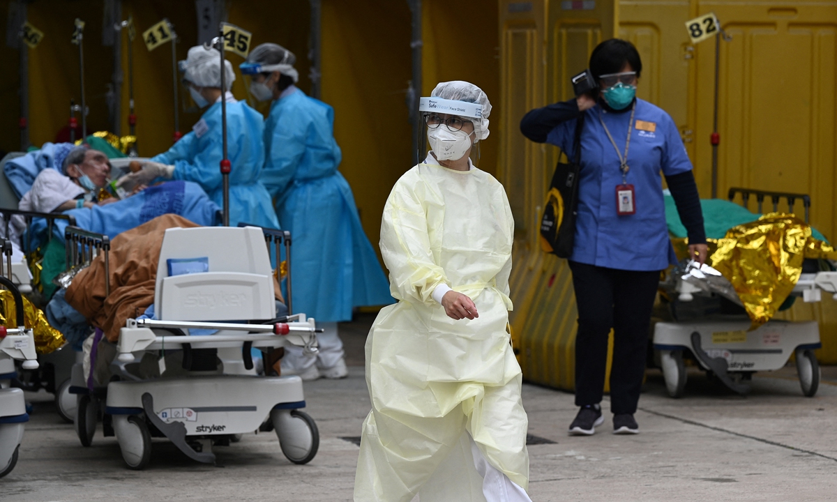 A nurse (center) walks through a temporary center for patients set up outside the Caritas Medical Centre in Hong Kong on February 16, 2022, as the city faces its worst COVID-19 wave to date. Photo: AFP