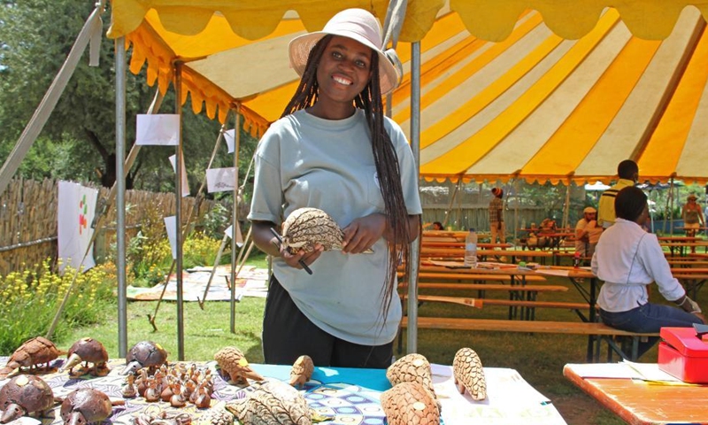 A volunteer displays pangolin replica products during an event to raise awareness on saving pangolin in Windhoek, Namibia, on Feb. 19, 2022.Photo：Xinhua