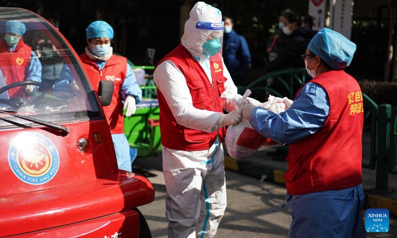 A volunteer takes vegetable packages from a staff member at Suzhou Industrial Park in Suzhou, east China's Jiangsu Province, Feb. 20, 2022.Photo:Xinhua