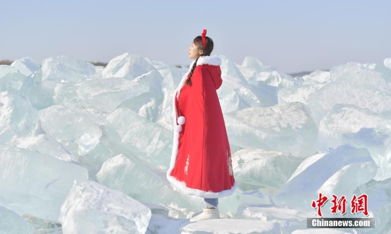 2022年2月23日，在中国东北吉林省长春市净月潭国家风景区，游客在一堆蓝色冰块前合影留念。（照片：中新社/张耀）