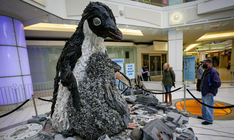 People look at a penguin art sculpture made from plastic marine debris during the 