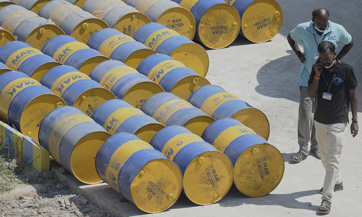 Workers walk past oil barrels at a filling station in Chennai, India on February 24, 2022. Oil prices jumped on the day amid Russia's military actions in Ukraine. Photo: AFP
