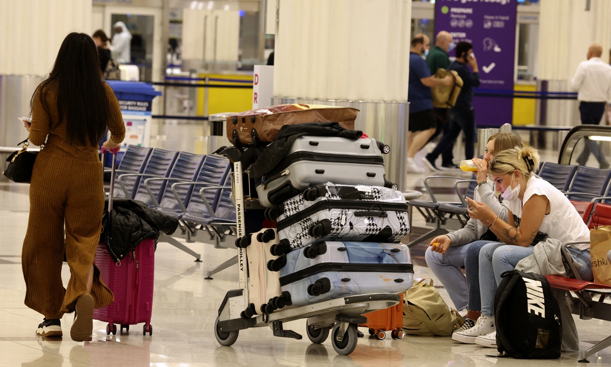 Travelers wait with their luggage pieces at Dubai International Airport on February 21, 2022. Photo: AFP