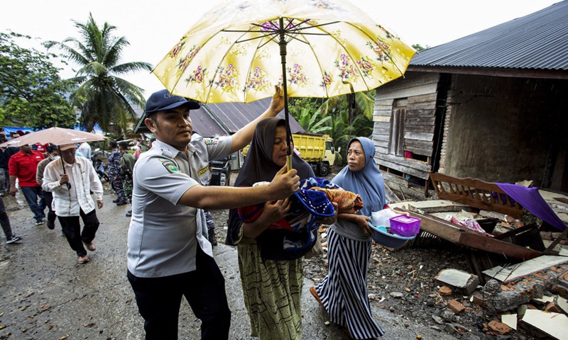 An official evacuates a woman with her baby after a revised 6.1 magnitude quake in Nagari Pinagar Village of Pasaman Barat district in West Sumatra, Indonesia, Feb. 25, 2022.(Photo: Xinhua)