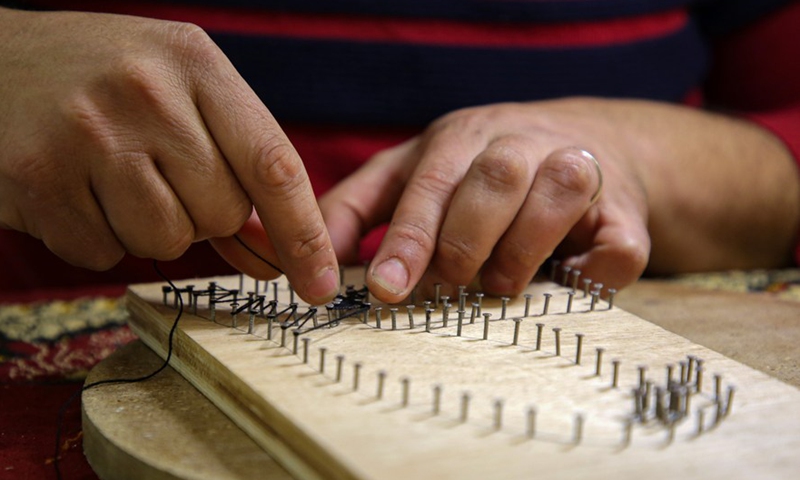 Picture taken on Feb. 24, 2022 shows Palestinian artist Naim Maarouf creating a pin-and-thread artwork at his house in Gaza City.Photo:Xinhua