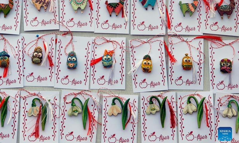 Small handmade figurines called Martisor are displayed during the Martisor Fair in Bucharest, capital of Romania, Feb. 26, 2022. Martisor is a small decoration tied with a red-and-white twisted string, given to women on the 1st of March as a token of appreciation, love or friendship and as a wish of health, being at the same time a symbol of the coming spring. (Photo by Cristian Cristel/Xinhua)